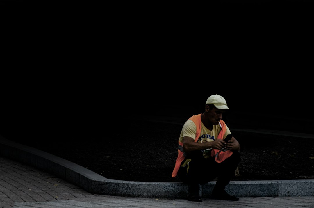 man in white shirt playing guitar sitting on concrete pavement