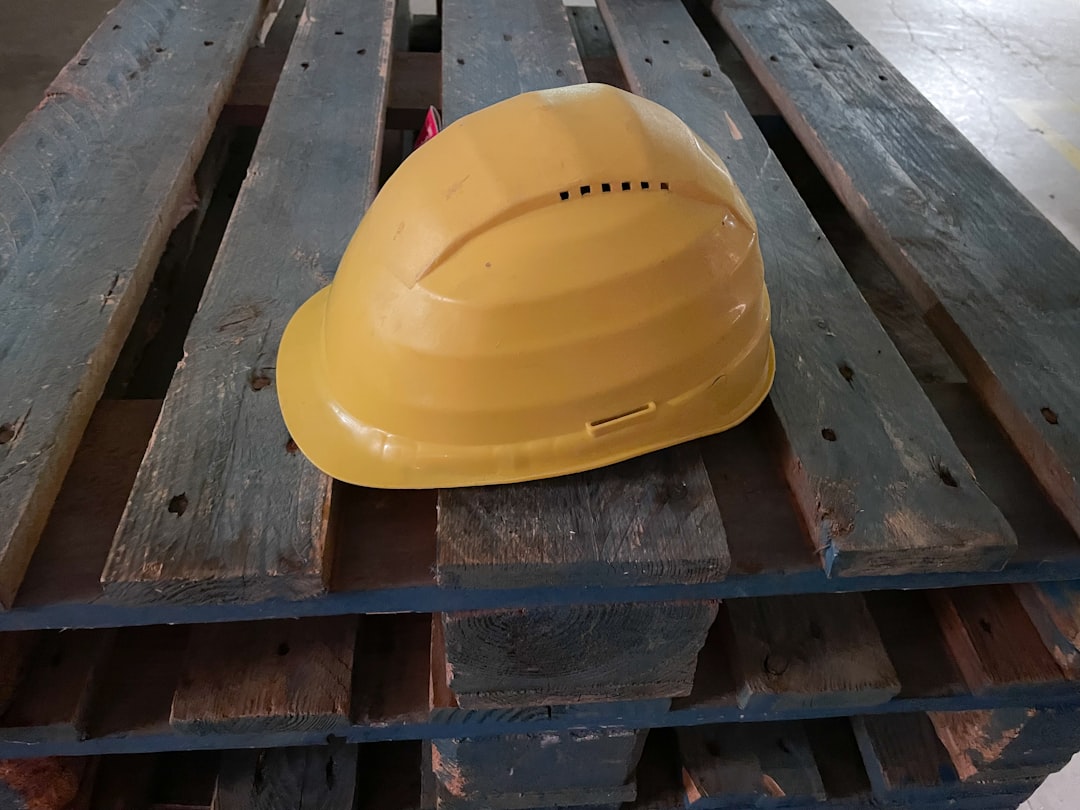 A yellow hard hat rests on a wooden pallet